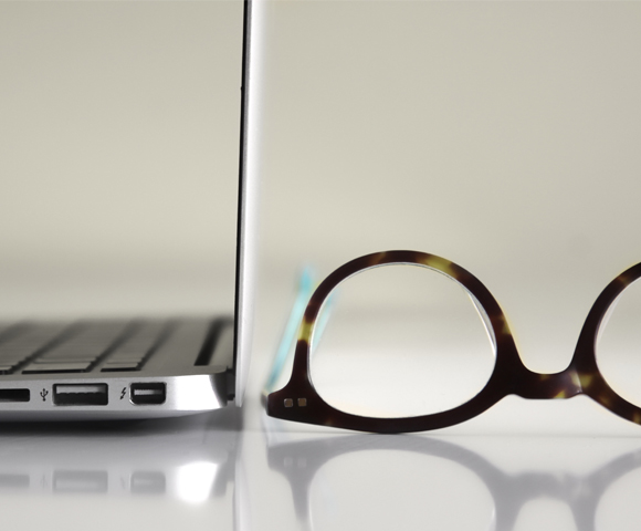 MacBook with prescription glasses lying on desk
