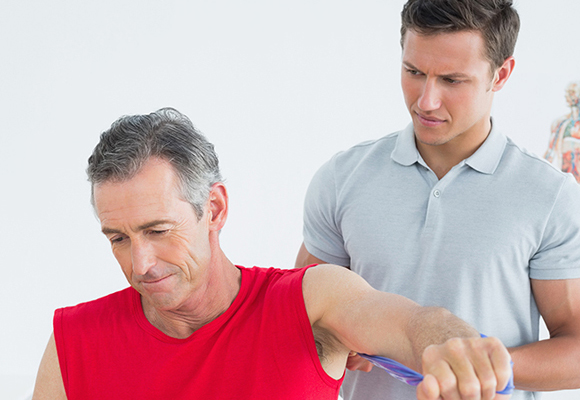 Athletic trainer assisting man in rehabilitation