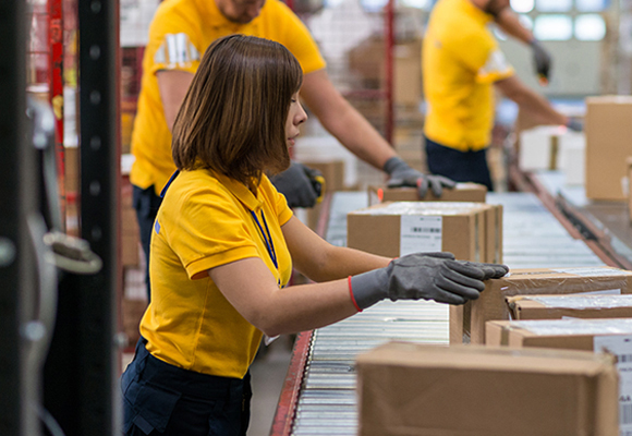 Staff lifting and moving boxes off assembly line