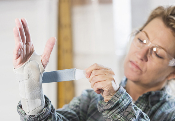 Female warehouse employee wrapping splint around her wrist